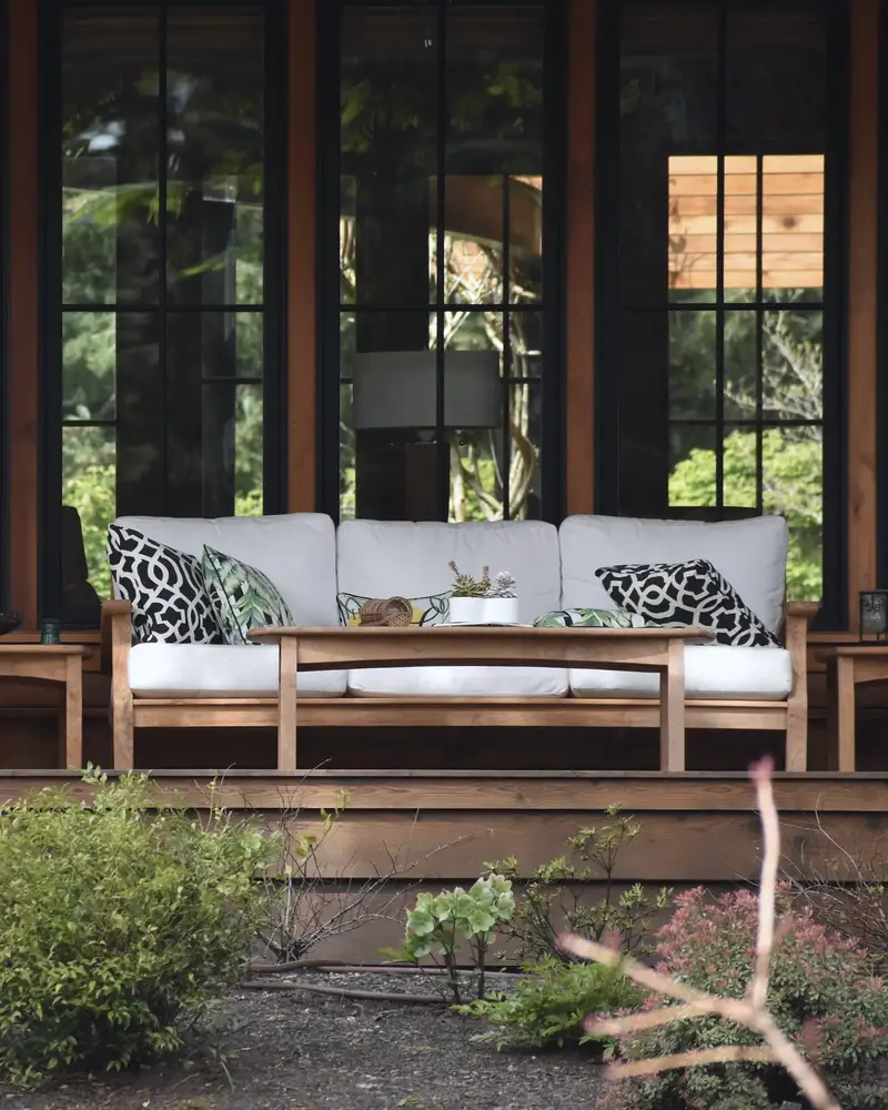 A covered porch with outdoor chairs and a garden