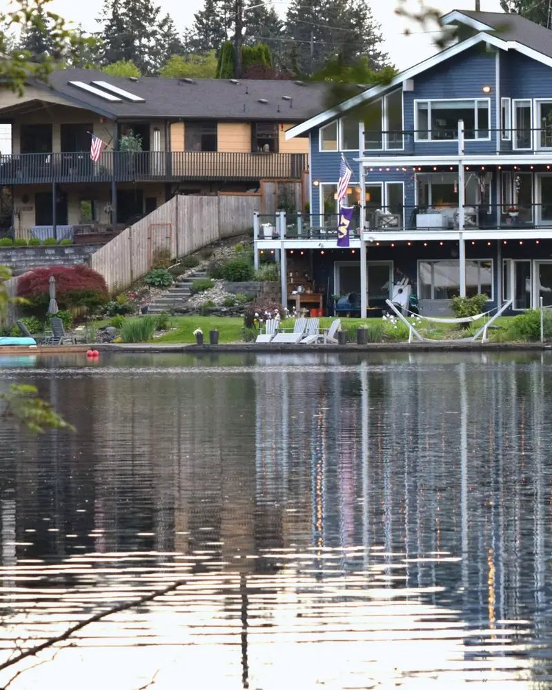 A blue waterfront house with decks above its own reflection